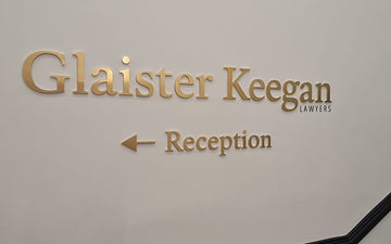 Wall-mounted 3D bronze lettering for Glaister Keegan Lawyers with directional arrow pointing to reception