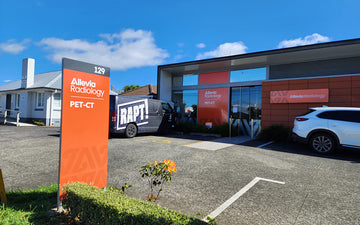 Exterior of Allevia Radiology PET-CT facility featuring bold branded signage, glass entry, and directional totem sign at 129 street address