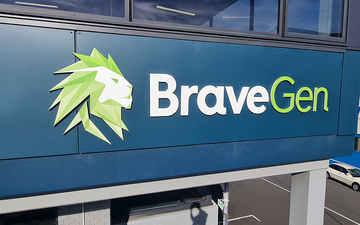 Exterior building signage for BraveGen featuring a geometric green lion logo and 3D lettering in white and lime green on a dark blue façade