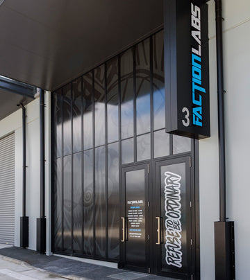 Modern black-framed storefront of Faction Labs with vertical signage and slogan ‘Refuse to Be Ordinary’ displayed on the door, set against graphic frosted glass panels