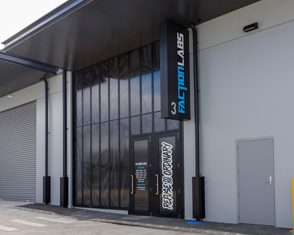 Modern exterior of Faction Labs at unit 3, featuring dark glass panels, bold signage reading “Refuse to Be Ordinary,” and a vertical Faction Labs logo.