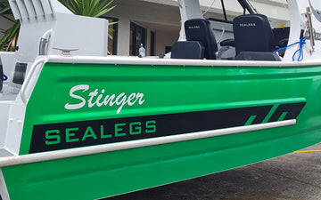 Green Sealegs Stinger boat with bold black and green branding on the side panel, featuring white script "Stinger" and black "SEALEGS" block lettering.