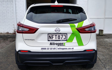 Rear view of a Nitrogenx-branded Nissan Qashqai featuring custom vinyl vehicle signage with contact details and bold green X logo.