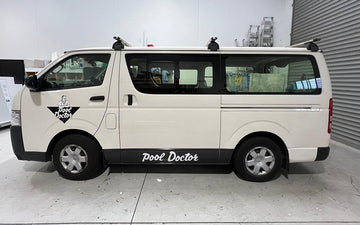 White van with black lower trim and "Pool Doctor" branding on the front door and side panel, parked indoors with visible pool service equipment inside.