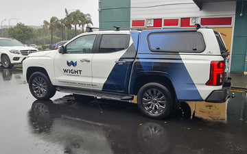 White and blue branded utility vehicle for Wight Aluminium, featuring a geometric logo and tagline for commercial facades, windows, and doors.