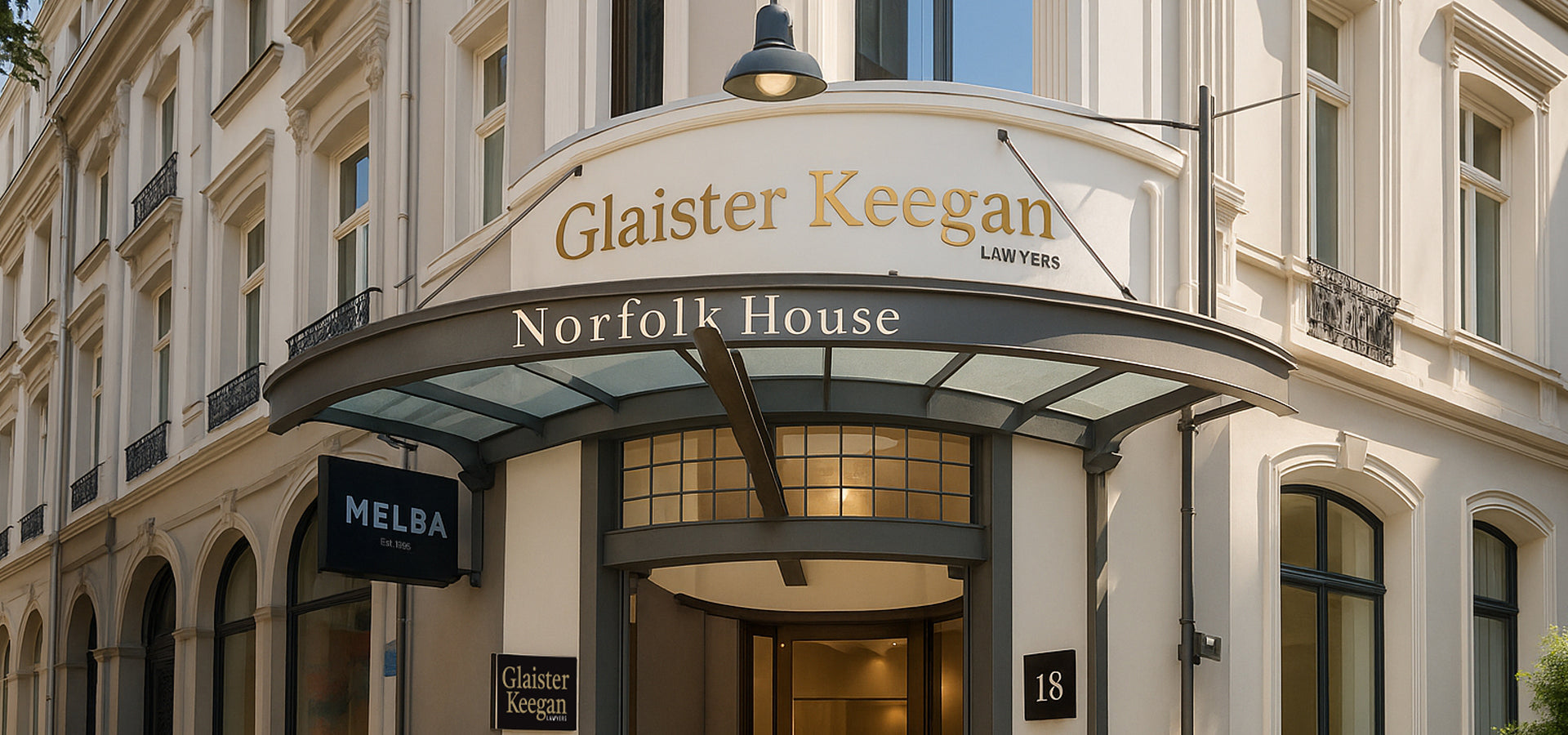 Elegant entrance of Glaister Keegan Lawyers at Norfolk House with curved glass awning, heritage architectural details, and the Melba café sign on the side.
