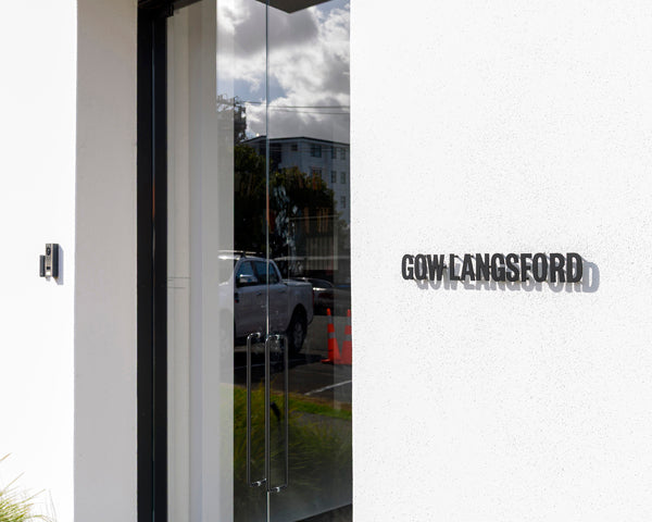 Close-up of black metal Gow Langsford lettering on a white exterior wall next to a glass door, showing clean and contemporary design.