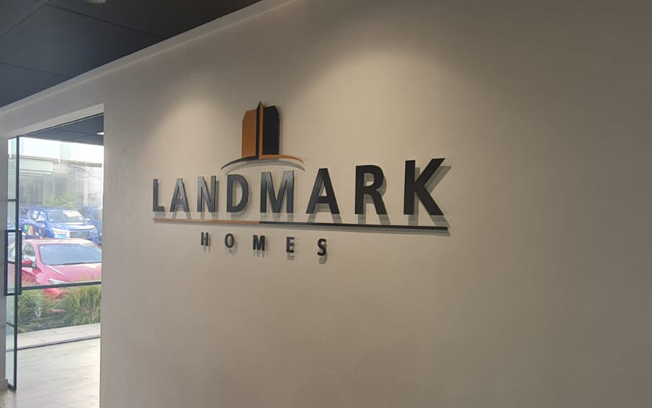 Interior office wall signage for Landmark Homes featuring 3D logo and lettering in black and bronze tones with sleek, professional finish