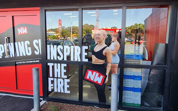 Bold window graphics at Nutrition Warehouse featuring large white text ‘Inspire the Fire’ and full-height images of athletic women promoting the NW brand